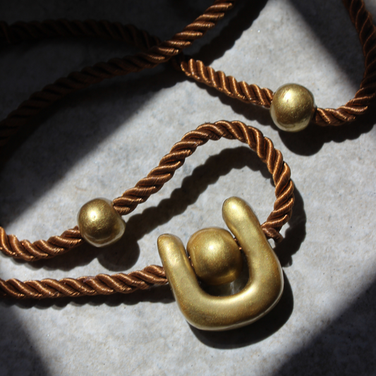 Collar hecho a mano con arcilla dorada y cuerda trenzada